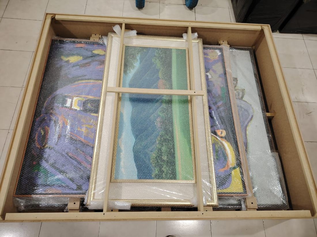 Cuadros y vidrios colocados con separadores dentro de un guacal de madera