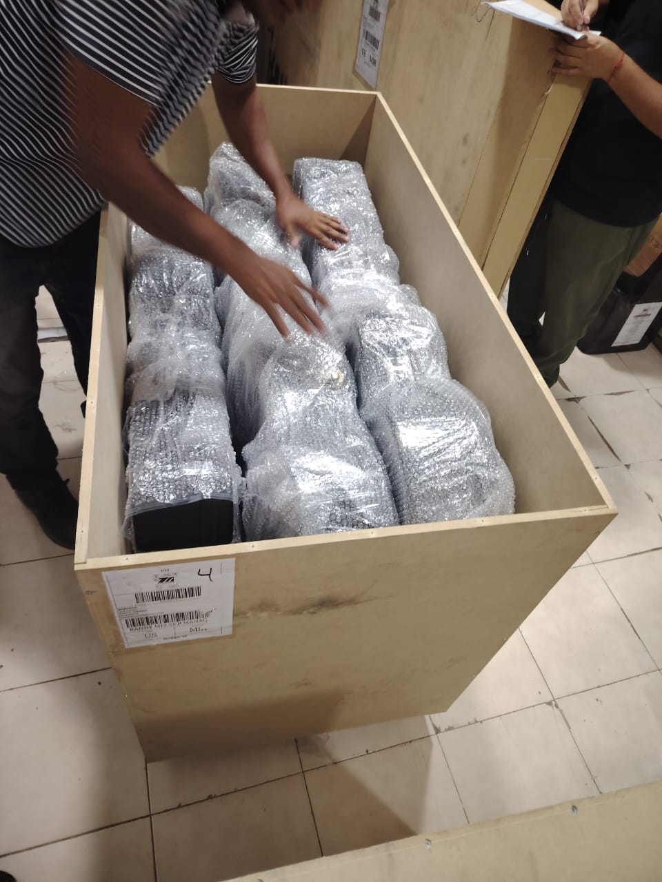 Piezas envueltas en plástico de burbuja colocadas dentro de un guacal de madera abierto