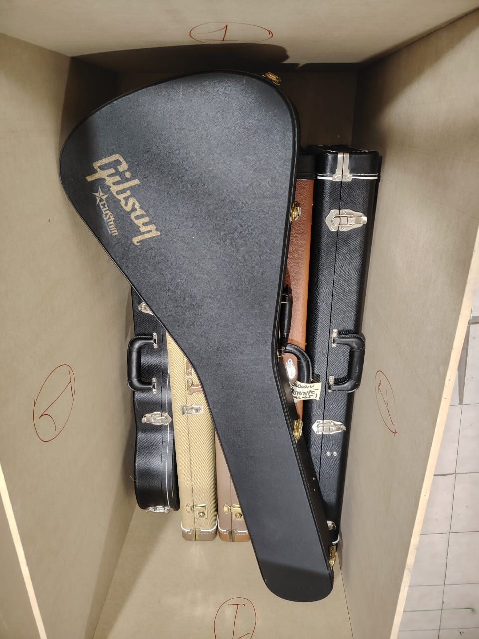 Estuches de guitarra acomodados dentro de un guacal de madera con separadores